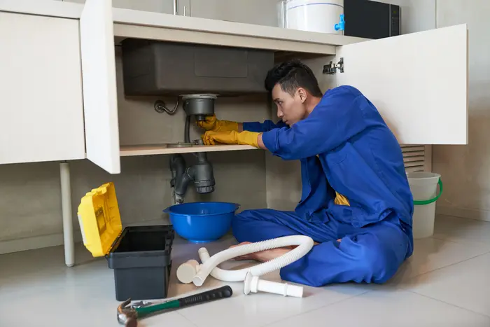 plumber-blue-overalls-clearing-blockage-drain